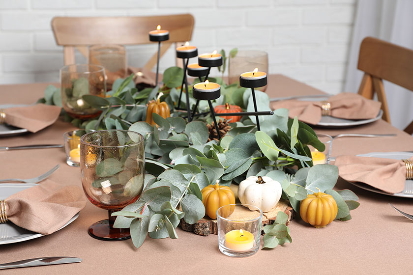 Autumn table setting with eucalyptus branches and pumpkins indoors